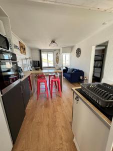 cocina y sala de estar con 2 taburetes rojos en Appartement 55 m2 - 2 chambres - avec vue mer, en La Bernerie-en-Retz