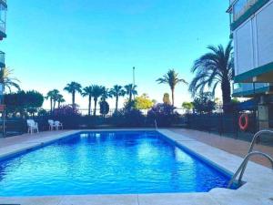 a swimming pool with blue water and palm trees at Apartamento Sea View By Solymar Holiday in Torre del Mar