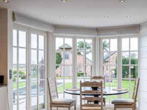 a dining room with windows and a table and chairs at Villa Blauw in De Panne