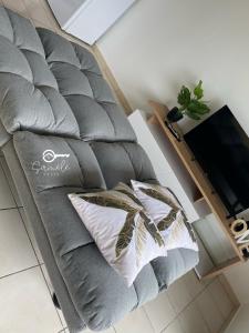 a grey chair with two pillows and a tv at Duplex cosy au cœur de Sinnamary, fleuve à pied- Samélé House in Sinnamary