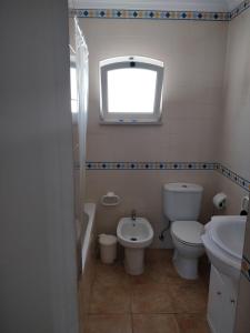 a bathroom with a toilet and a sink and a window at Cozy Apartment Cabanas de Tavira in Cabanas de Tavira
