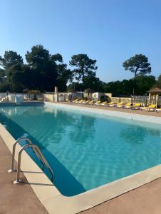 une grande piscine avec de l'eau bleue et des chaises dans l'établissement Mh 25 Les Genêts Ronce les bains, à La Tremblade