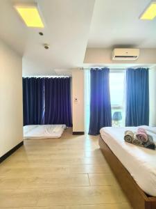 a bedroom with two beds and blue curtains at 2 Bedroom unit near airport in Lapu Lapu City +11 photos