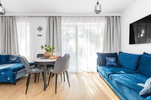 a living room with a blue couch and a table at APARTAMENTY MIERZEJA - STEGNA PARK II, MEDIUM, 500 m od plaży, Bezpłatny Meleks in Stegna