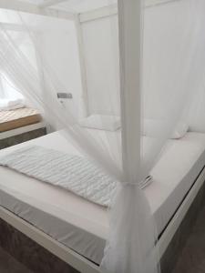 a white bed with a mosquito net on it at C-Born in Hikkaduwa