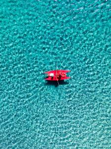 a red boat in the middle of the water at Hotel Dei Pini in Alghero