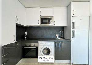 een keuken met een wasmachine en een magnetron bij DOMuum Holidays - POSIT MAR in Cambrils