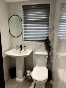 a white bathroom with a toilet and a sink at Charming Cosy Cottage in Bollington Village in Bollington +17 photos