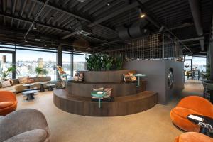 a waiting room with orange chairs and tables and windows at fabrik studio apartments in Chemnitz