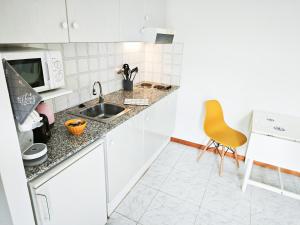 a white kitchen with a sink and a microwave at El Penell Estudi Garbí in Vilamaniscle