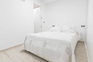a white bedroom with a bed and a mirror at Apartamentos Arena y Cairo in Murcia