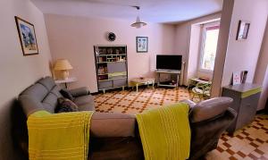 a living room with a couch and a tv at La Maison du Soleil in Saint-Gaudéric