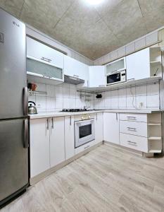 eine Küche mit weißen Schränken und Geräten aus Edelstahl in der Unterkunft Уютная квартира на Тверская 5, пр Правды, клиника Рохманова in Dnipro