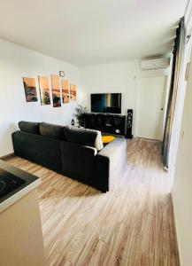 ein Wohnzimmer mit einer schwarzen Couch und einem Holzboden in der Unterkunft Apartamento costero Atardecer dorado in Las Galletas