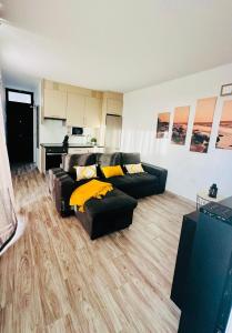 ein Wohnzimmer mit einem schwarzen Sofa und gelben Kissen in der Unterkunft Apartamento costero Atardecer dorado in Las Galletas