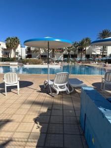 zwei Stühle und ein Sonnenschirm neben einem Swimmingpool in der Unterkunft Apartamento costero Atardecer dorado in Las Galletas