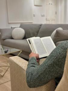una persona seduta su un divano che legge un libro di CoruñaFlat Apartments - Centro A Coruña a La Coruña