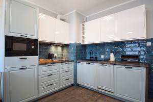 a kitchen with white cabinets and a microwave at RentPlanet - Perłowa Przystań in Sianozety +9 photos