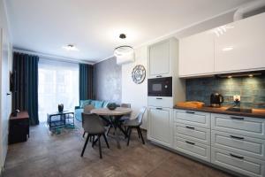 a kitchen with white cabinets and a table with chairs at RentPlanet - Perłowa Przystań in Sianozety