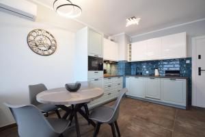a kitchen with a table and chairs and a clock on the wall at RentPlanet - Perłowa Przystań in Sianozety