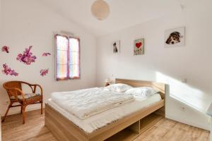 a bedroom with a bed and a chair and a window at Maison moderne à 80m de la plage - 6 personnes in La Guérinière
