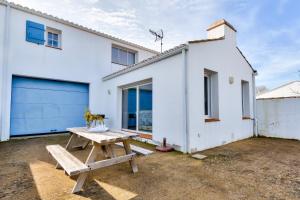 a white house with a picnic table in front of it at Maison moderne à 80m de la plage - 6 personnes in La Guérinière