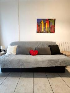a gray couch with a red heart on it in a room at maison de tourisme aux sables d'olonne in Les Sables-dʼOlonne