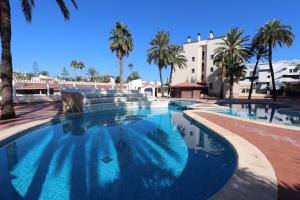 a large swimming pool with palm trees and a building at Seaside Serenity in Denia in Denia