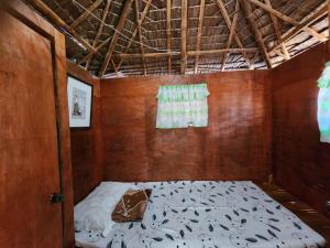 a bed in a room with a wooden wall at JFive Homes by the Sea in Lianga
