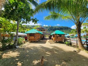 a village with cottages and palm trees on a beach at JFive Homes by the Sea in Lianga
