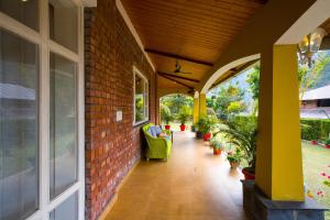a porch with a brick wall and chairs and plants at Alaya Stays Country Ville - 3 BHK Pet Friendly Villa with Lush Garden & Kids Room in Kokliyal Gaon