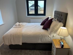 a bedroom with a large bed and a table with a lamp at Pineapple Cottage in Thorndon