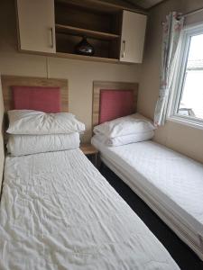 two twin beds in a room with a window at 6 Berth Caravan with garden - Brightholme Holiday Park in Brean
