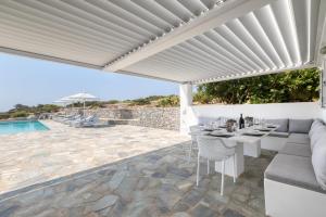 pérgola blanca sobre un patio con mesa y sillas en Villa Dioni, en Santa Maria