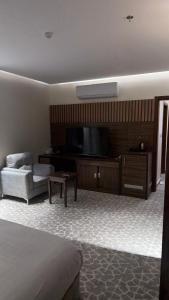 a hotel room with a bed and a flat screen tv at Alula Oasis1 in AlUla
