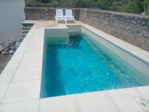 a swimming pool with two chairs next to a wall at Refugio de Soles in Cachí
