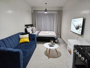 a living room with a blue couch and a bed at The Haven Tsavo in Ongata Rongai 