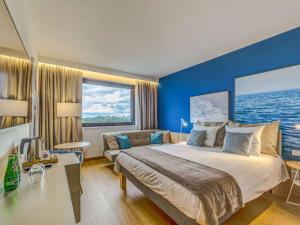a bedroom with a large bed and a blue wall at Novotel Gdańsk Marina in Gdańsk