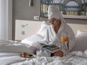a woman sitting on a bed reading a book at Pullman Paris Tour Eiffel in Paris