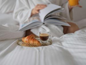 a woman laying in bed reading a book with a cup of coffee and a plate at Pullman Paris Tour Eiffel in Paris