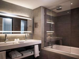 a bathroom with a sink and a tub at Pullman Paris Tour Eiffel in Paris