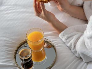 a person sitting on a bed with a tray with a glass of orange juice at Pullman Paris Tour Eiffel in Paris