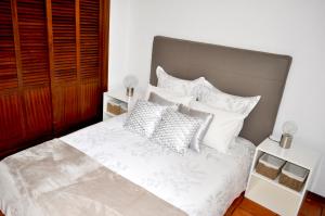 a bedroom with a bed with white sheets and pillows at Refúgio Guest House in São Vicente