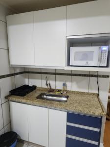 a kitchen with a sink and a microwave at Studio no centro in Poços de Caldas