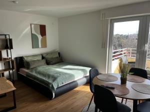 a bedroom with a bed and a table and a window at Zentrales Apartment an der BigBox in Haslach