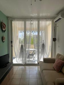 un soggiorno con un divano e una porta scorrevole in vetro di Casa-vacanze mare a Isca Marina Altre 2 foto