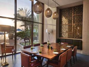 a dining room with a wooden table and chairs at Fairmont Ajman in Ajman 