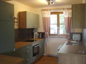 a kitchen with green cabinets and a window at Granerhof Ferien in Peißenberg