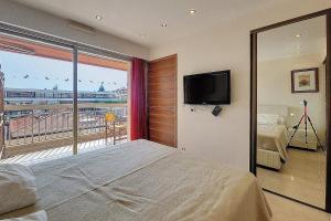 Schlafzimmer mit einem Bett und einem Balkon mit einem TV in der Unterkunft HENRI CAMILLE REAL ESTATE - Kent - Huge 2 bedrooms appt - 5 min Croisette in Cannes + 5 Fotos