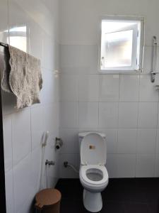 a white bathroom with a toilet and a window at Villa Uppugama in Etagama